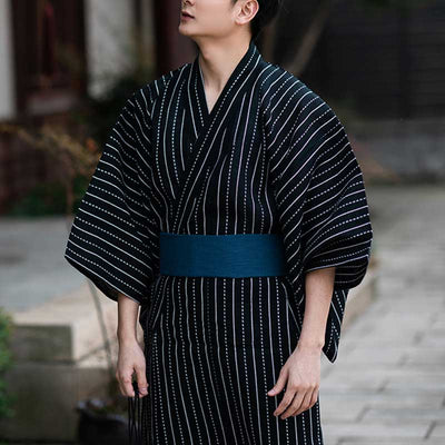A man is dressed in a plus size black kimono cosplay. The yukata is fastened with a Japanese obi belt. Cotton material