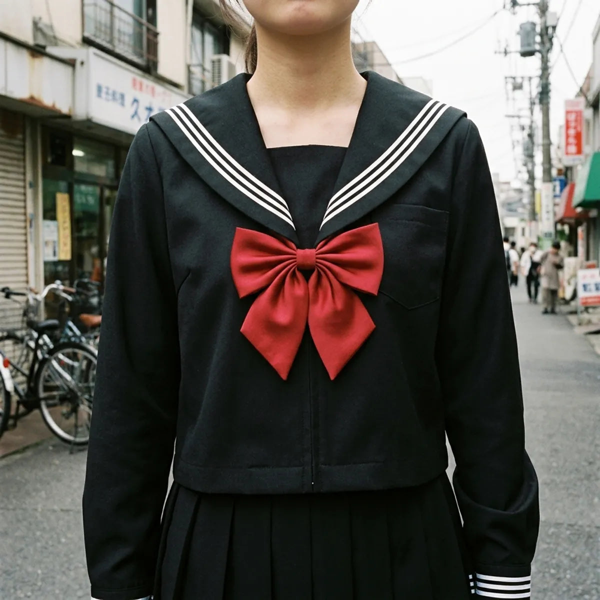 Close view of the black sailor collar with three white stripes and the red satin bow