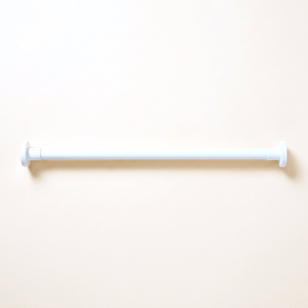 White adjustable tension rod for noren with round end caps on a cream studio background