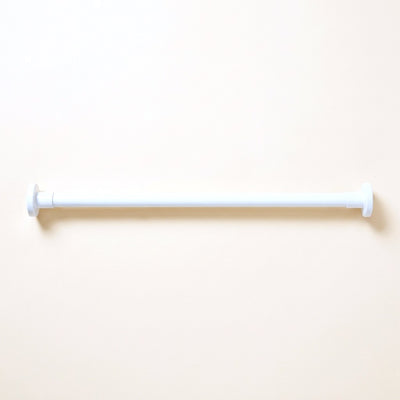 White adjustable tension rod for noren with round end caps on a cream studio background