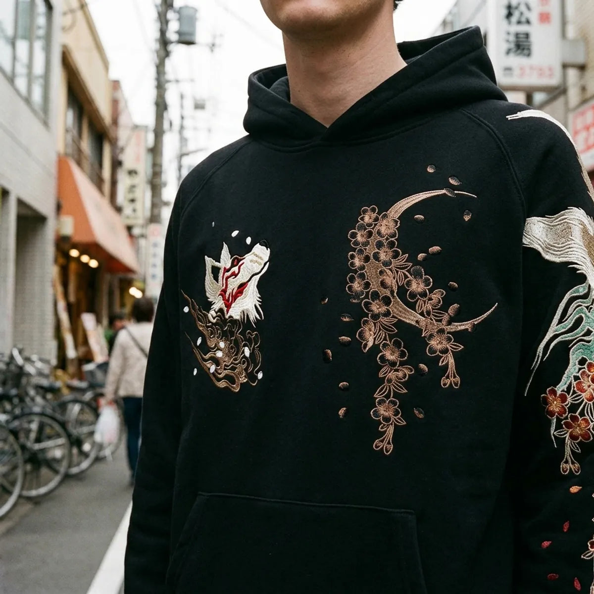 Close view of the bronze crescent moon and cherry blossoms embroidered on the chest of the hoodie
