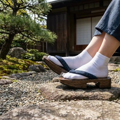 Sandal Japanese Man in dark-stained wood geta with indigo hanao straps, front view in Japanese garden