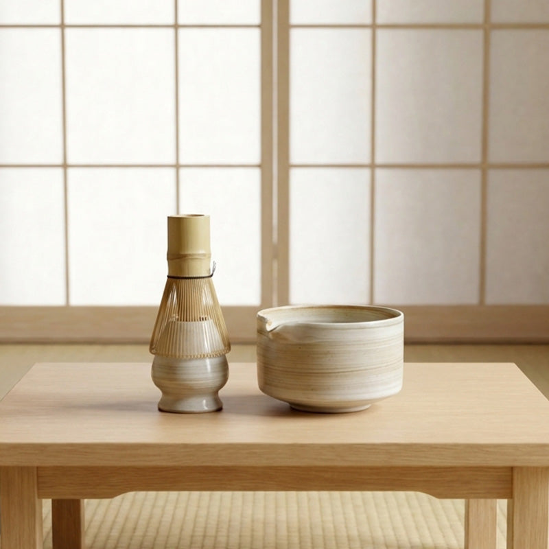 Two ceramic items from a set of matcha on a wooden table with a tiled wall background