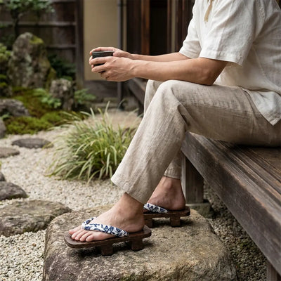 Shoe Japanese Wood worn with white tabi socks by a seated man in a Japanese garden
