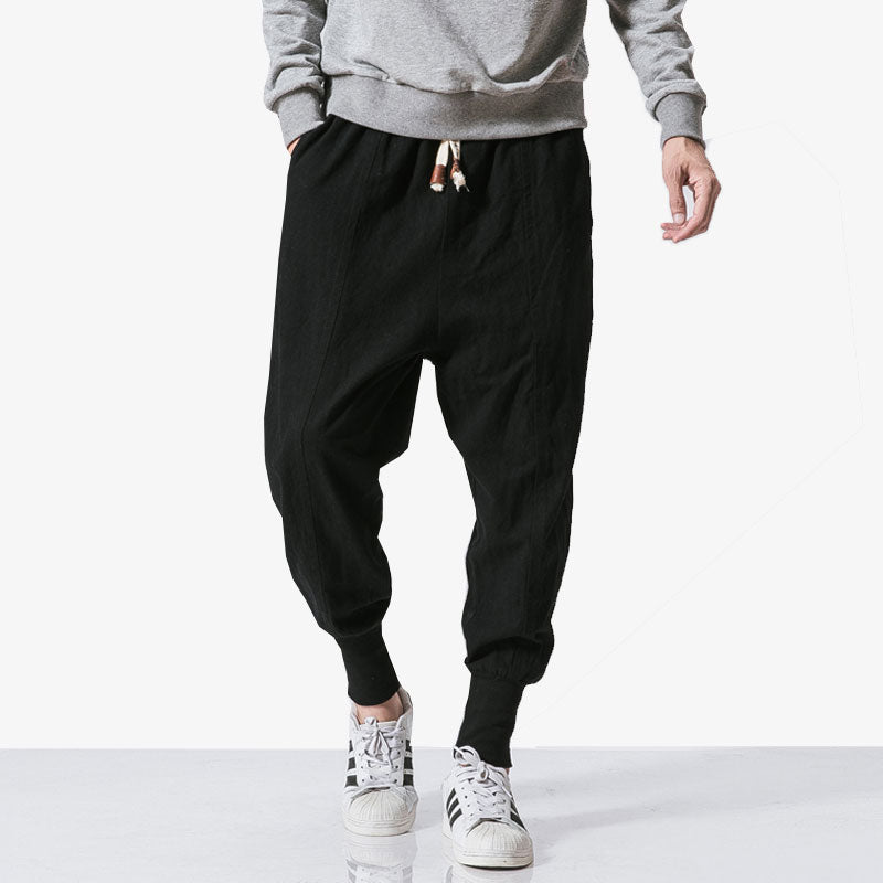 A man wearing streetwear pants with adidas sneakers and a grey sweatshirt