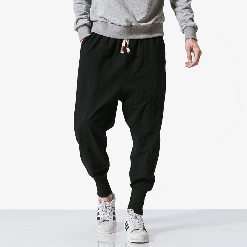 A man wearing streetwear pants with adidas sneakers and a grey sweatshirt