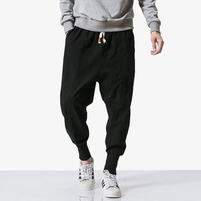 A man wearing streetwear pants with adidas sneakers and a grey sweatshirt