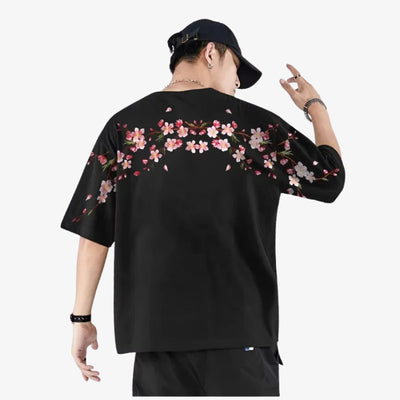 Person wearing a black  streetwear sakurashirt with floral designs on a white background