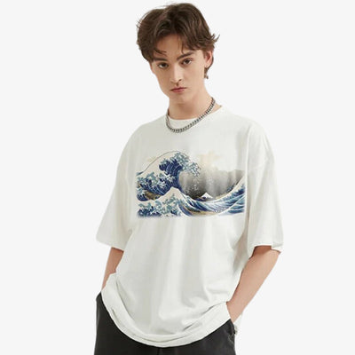 A man is wearing a the great wave off kanagawa t shirt. He is standing with his hands in his pockets.