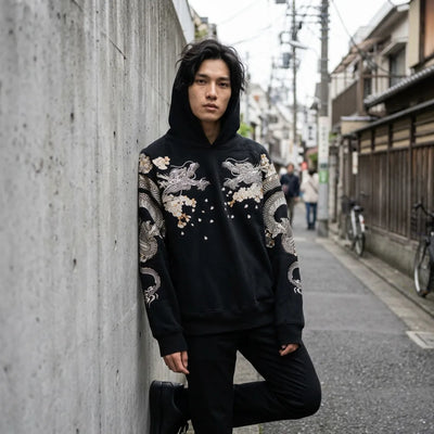 Tokyo streetwear hoodie worn with the hood up, leaning against a concrete wall in a Harajuku side street