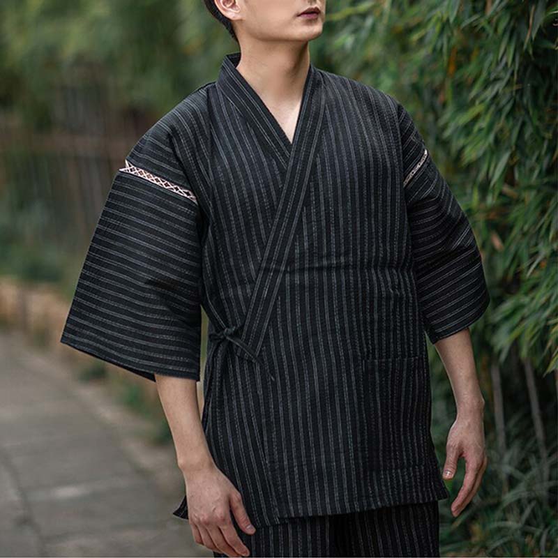 A man is dressed in  Traditional Japanese pajamas Mens.. The light kimono is made with cotton. Color is black with stipes