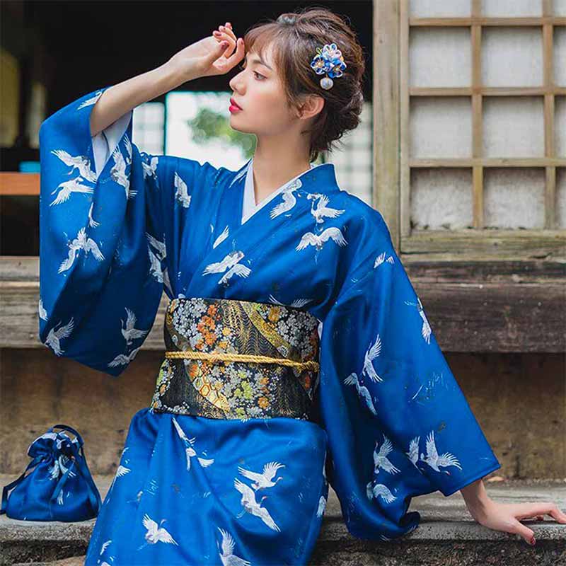 a traditional female kimono made with blue color, printed with tsuru birds symbols. The floral obi bely ties the geisha kimono