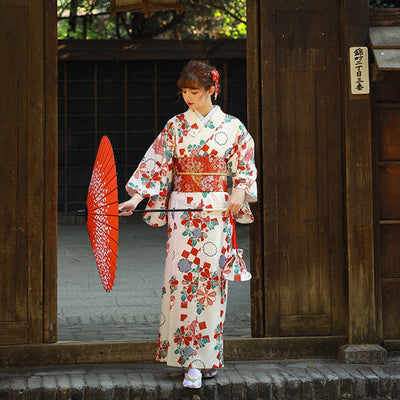 Traditional flower kimono dress featuring sakura and fukiwa motifs. The woman holds a Japanese umbrella. The Japanese kimono is closed thanks to a red japanese belt (Obi belt)