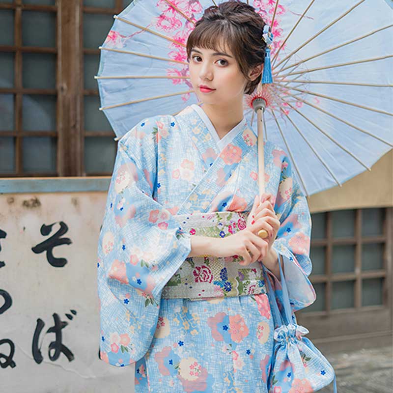 Traditional geisha dress kimono with printed Japanese floral designs. The woman elegantly holds a wagasa, showcasing the intricate patterns