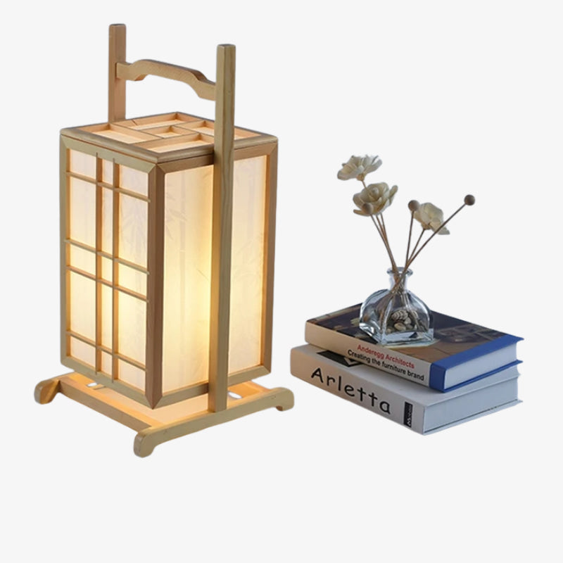 Wooden traditional japanese floor lamp​ with a soft glow next to books and a small vase with flowers on a white background