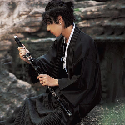 For samurai style, wear a Traditional Mens kimonos. The Japapanese men holds a katana sword in his hand. Cotton fabric of Japanese kimono is cotton and color is black with white stripes on the collar