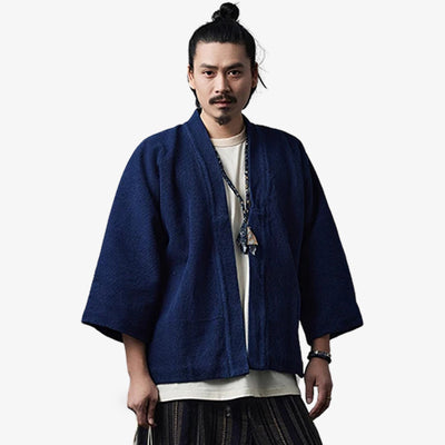 a Japanese man is dressed with a Vintage haori jacket with blue indigo minimalist design. he stands with a white harajuku style shirt and a Japanese hakama pants for men. Material of the blue kimono jacket is cotton