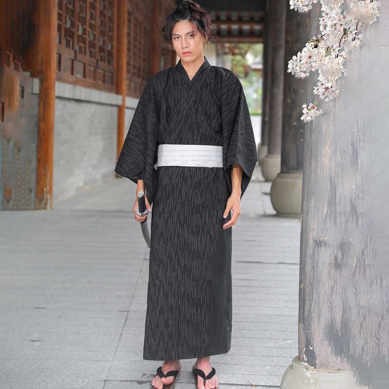 A Japanese man is wearing a checkered yukata kimono and a white belt obi. 