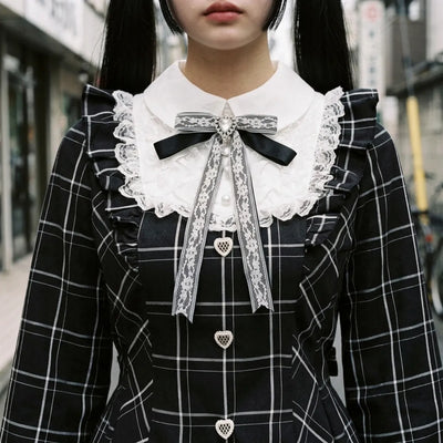 Close view of the white lace sailor collar, the ribbon bow and the heart shaped buttons