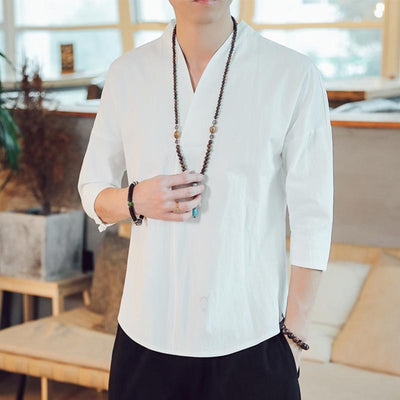 A man dressed with white zen Japanese shirt for a casual outfit. He wears a black pant