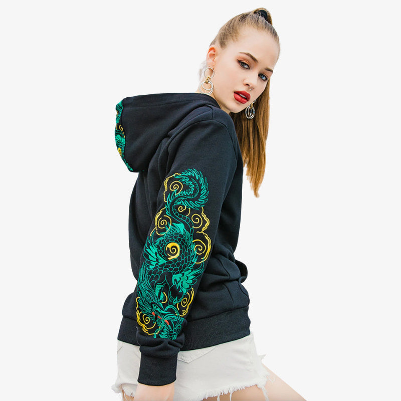 Woman wearing a black hoodie with green and gold embroidery on a white background