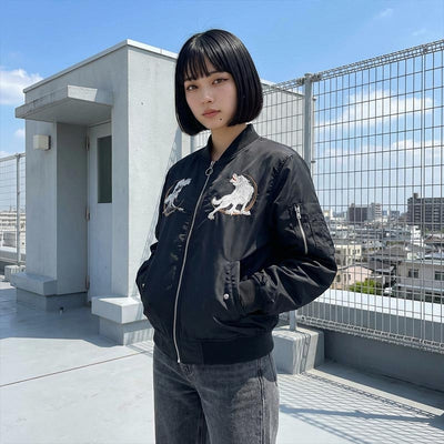 Woman wearing a black bomber Sukajan jacket with white wolf designs on a Tokyo rooftop with cityscape background
