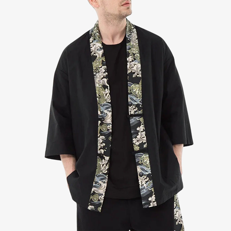This Japanese kimono is a black haori jacket. The man has his hands in his pockets and is also wearing a black t-shirt.