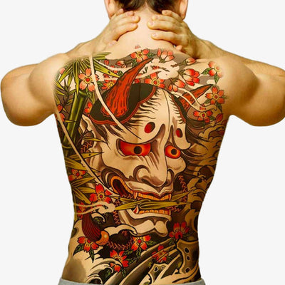 Person with a detailed Japanese temporary tattoo of a hannya mask and nature elements on their back representing Sakura flowers