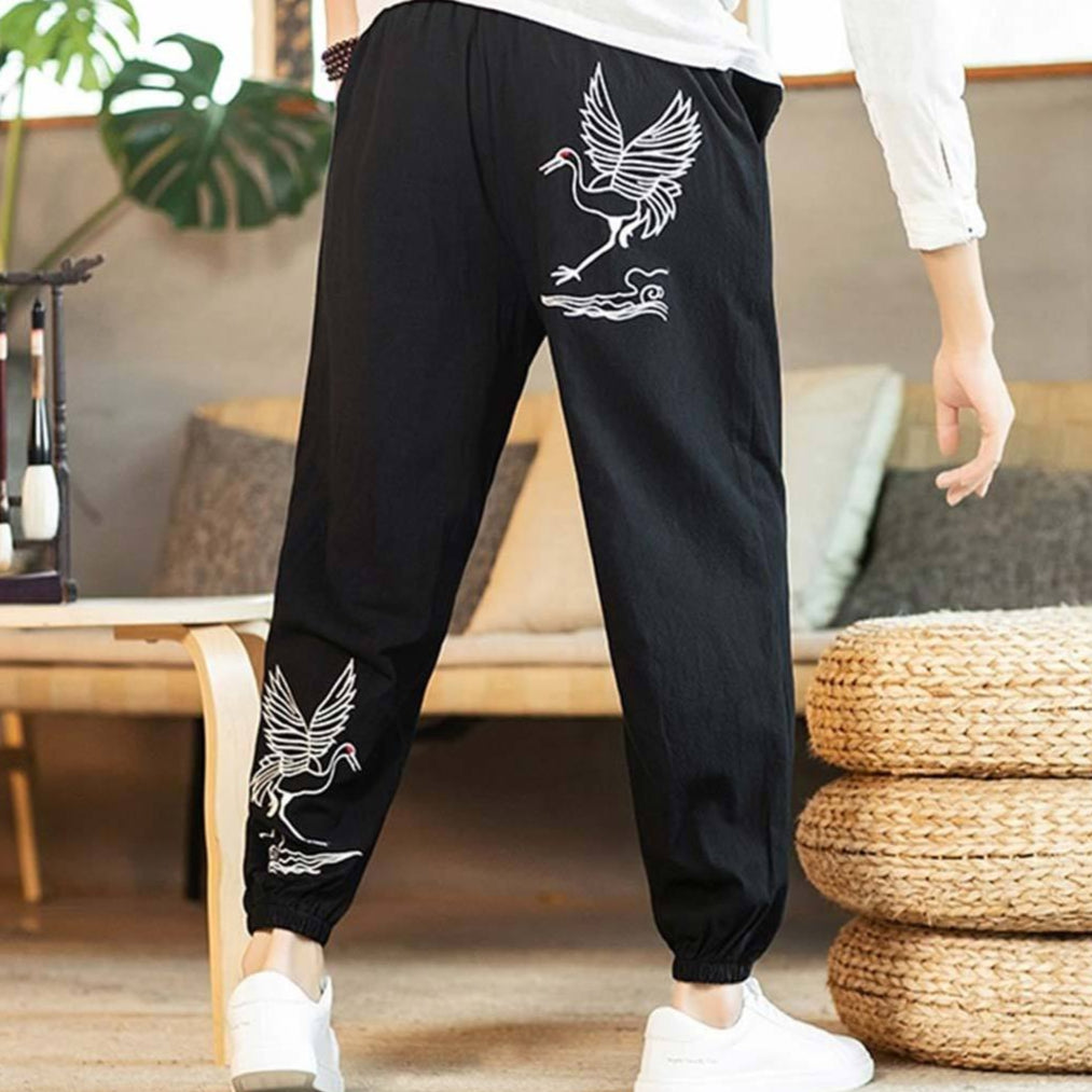 Person wearing black-japanese-cranes-pants with white bird designs in a casual setting.