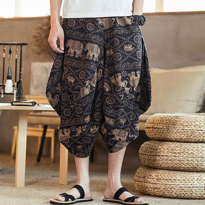 A person wearing black fluid pants japan-with a golden elephant and geometric pattern.