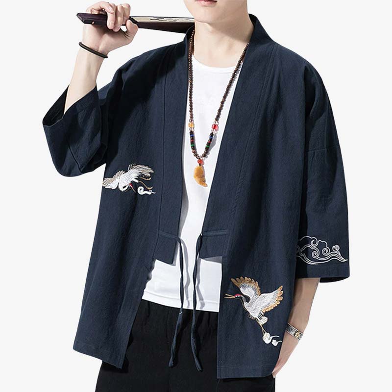 A man wearing a navy blue Haori jacket men with hand-embroidered Japanese Tsuru patterns, paired with a white shirt and black pants.