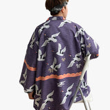 A Japanese man from the back is wearing a blue haori tokyo jacket with Japanese Tsuru crane motifs.