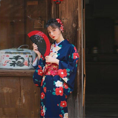 Japanese kimonos robe featuring intricate flower designs on high-quality fabric. The woman is standing with a long kimono fastened by an Obi belt.