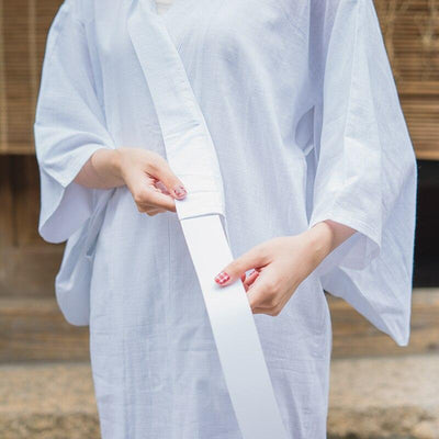 A woman holds in her hand a white kimono nagajuban belt
