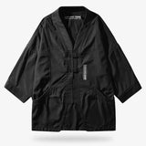 This techwear haori is black. It is a kimono jacket worn with a Japanese streetwear style.