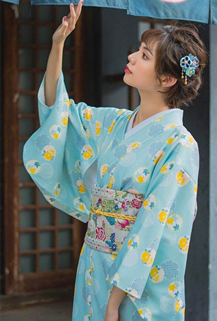 Traditional Japanese kimono wedding dress featuring intricate designs and soft fabric. The bride stands with her long kimono secured by a traditional large Obi belt, her hair adorned with a Japanese Kanzashi